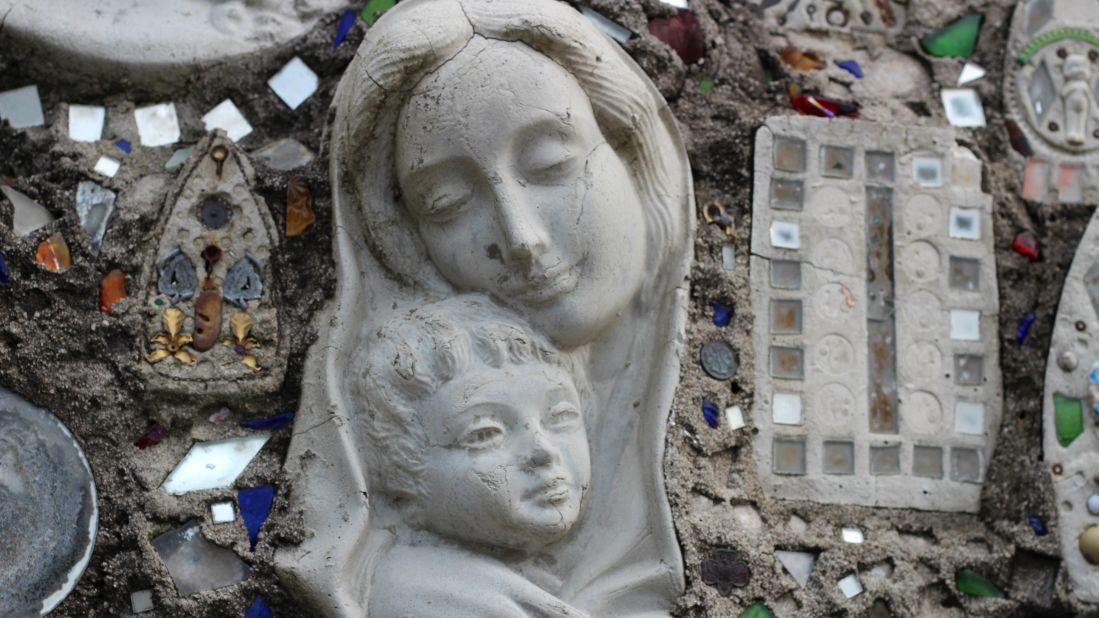 Madonna and child join thousands of glass fragments and objects embedded in the walls of the Mosaic Garden.