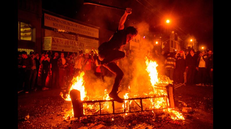 A man jumps over a burning couch in San Francisco's Mission District after the San Francisco Giants beat the Kansas City Royals to win the World Series on Wednesday, October 29.