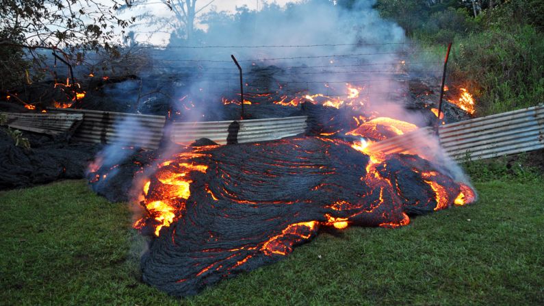 Lava from <a href="http://www.cnn.com/2014/10/28/us/gallery/kilauea-volcano/index.html">the Kilauea volcano</a> pours past a boundary fence in Pahoa, Hawaii, on Tuesday, October 28. The flow has recently picked up speed, prompting emergency officials to close part of the main road through town and tell residents to be prepared to evacuate.