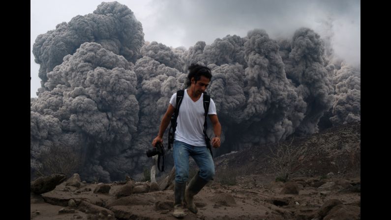 Ash clouds from the Mount Sinabung volcano are seen behind a photographer as he runs Saturday, October 25, on Indonesia's Sumatra Island. Mount Sinaburg began erupting last year.