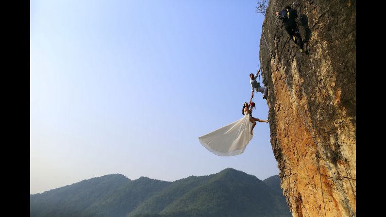Zheng Feng, an amateur climber, takes wedding pictures with his bride on a cliff in Jinhua, China, on Sunday, October 26.
