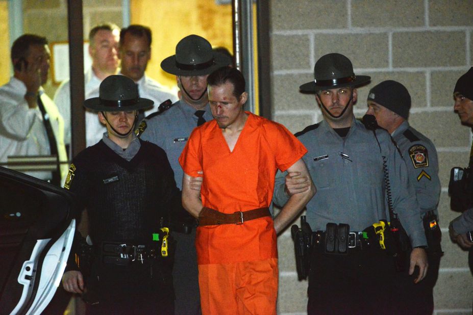 State troopers escort Eric Matthew Frein from the state police barracks in Blooming Grove, Pennsylvania, on October 31, 2014. Frein, who is accused of killing a Pennsylvania state trooper and wounding another, was found at an abandoned airport near Tannersville, Pennsylvania, authorities said. He had been on the run for nearly two months.