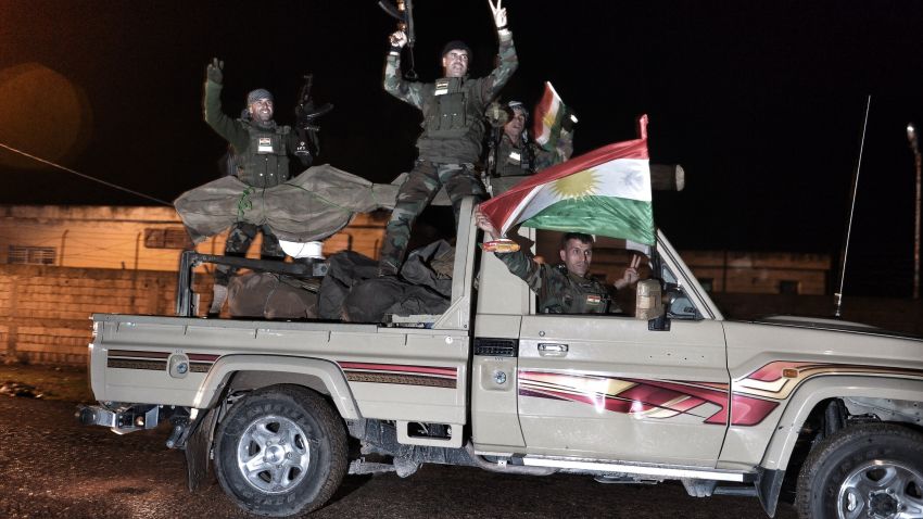Kurdish peshmerga fighters gesture and wave a Kurdish flag from a military vehicle armed with a heavy infantry weapon as they ride towards the Syrian town of Kobane, also known as Ain al-Arab, from the border town of Suruc, in the Turkish southeastern Sanliurfa province, on October 31, 2014. Kurdish peshmerga reinforcements entered Syria from Turkey late on October 31 to bolster defenders in the key border town of Kobane which is under assault by Islamic State group jihadists. AFP PHOTO/STRINGER (Photo credit should read STRINGER/AFP/Getty Images)