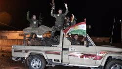 Kurdish peshmerga fighters gesture and wave a Kurdish flag from a military vehicle armed with a heavy infantry weapon as they ride towards the Syrian town of Kobane, also known as Ain al-Arab, from the border town of Suruc, in the Turkish southeastern Sanliurfa province, on October 31, 2014.