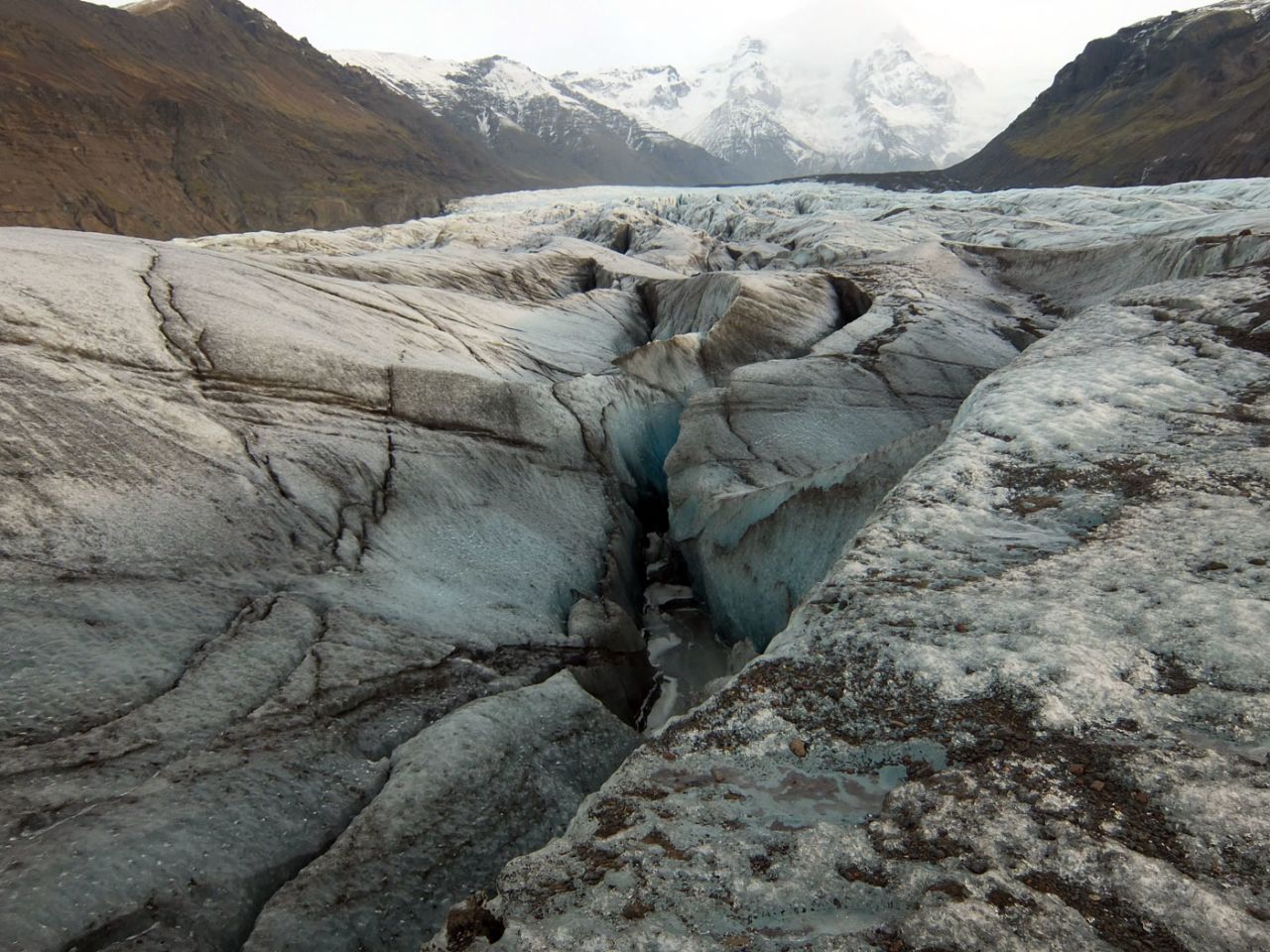 The glacier appears marbled where crevasses have opened then closed again as the ice moves down the mountain. The dirt is morraine -- debris torn up by the glacier.