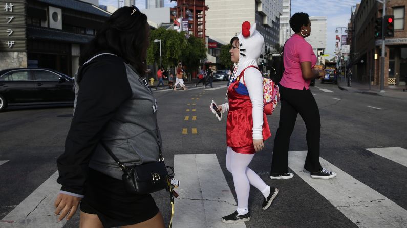 A girl dressed as Hello Kitty crosses the street.
