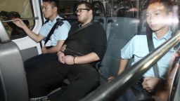 This handout picture taken and released by Apple Daily on November 3, 2014 shows British expatriate Rurik Jutting (C) sitting cuffed between police as he is driven to court in Hong Kong, following a holding charge of two counts of murder being laid against him after the grim discovery of two women's bodies, including one in a suitcase, in his upmarket apartment, police said. Jutting was arrested after calling police to his flat on the 31st floor of the residential block in the popular expatriate district of Wanchai in the early hours of November 1