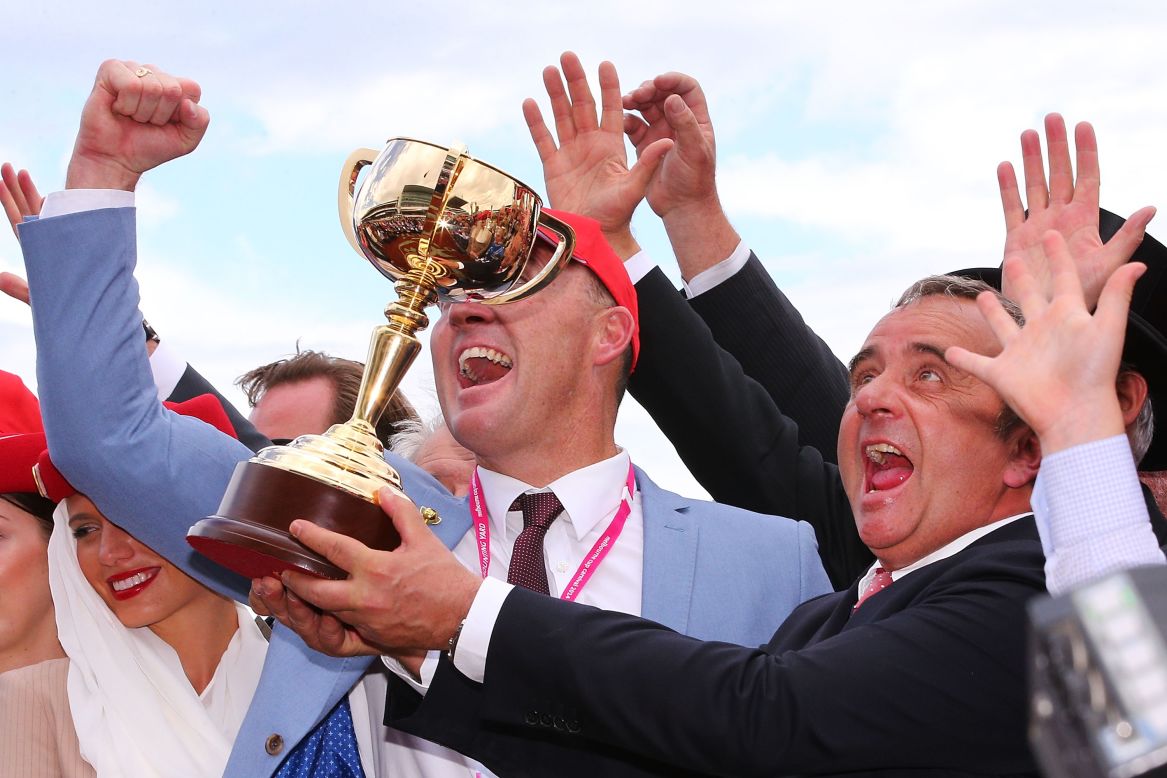 Euphoric Protectionist trainer Andreas Wohler celebrates with the trophy after winning race 7 of the prestigious Melbourne Cup.