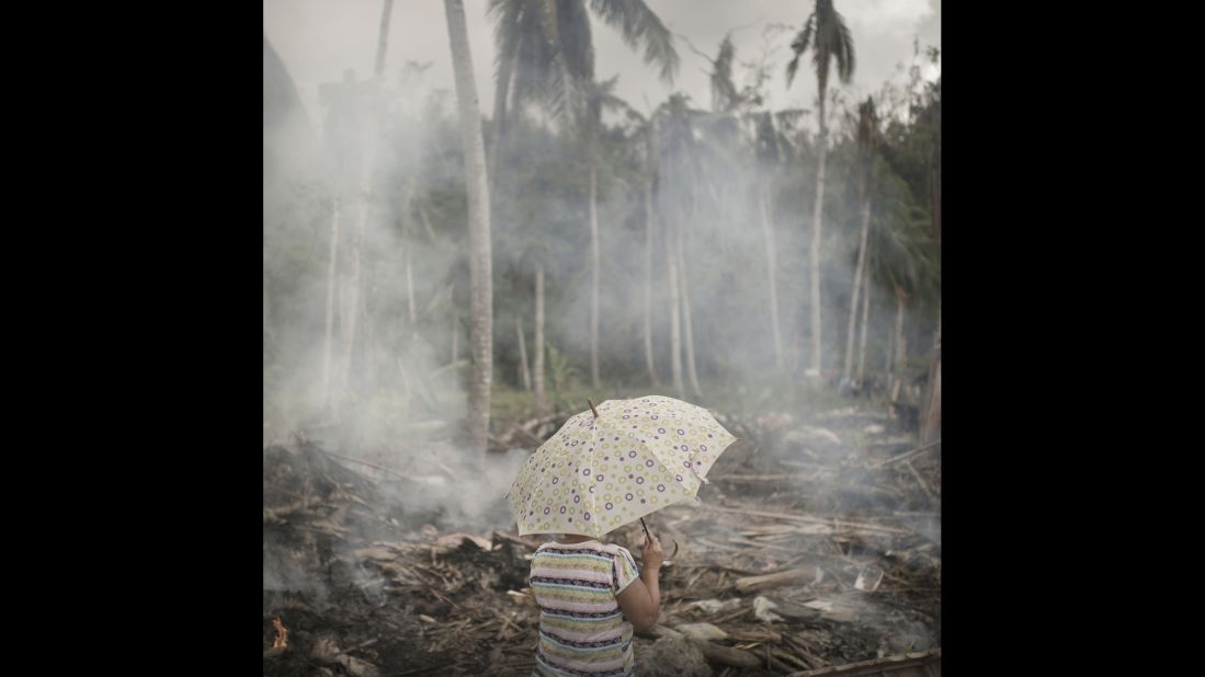 A woman wanders around her neighborhood three weeks after the typhoon. Four million people lost their homes due to Haiyan. People made fires to get rid of the piles of rubbish and debris. Legaspi, December 2013.