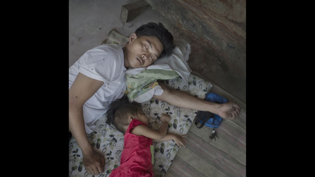 A father rests with his daughter in the shadow of a stranded ship in the harbor of Tacloban. After six months, 2 million people were still living in tents or temporary shelters. In September, the typhoon season began again. Tacloban, May 2014.