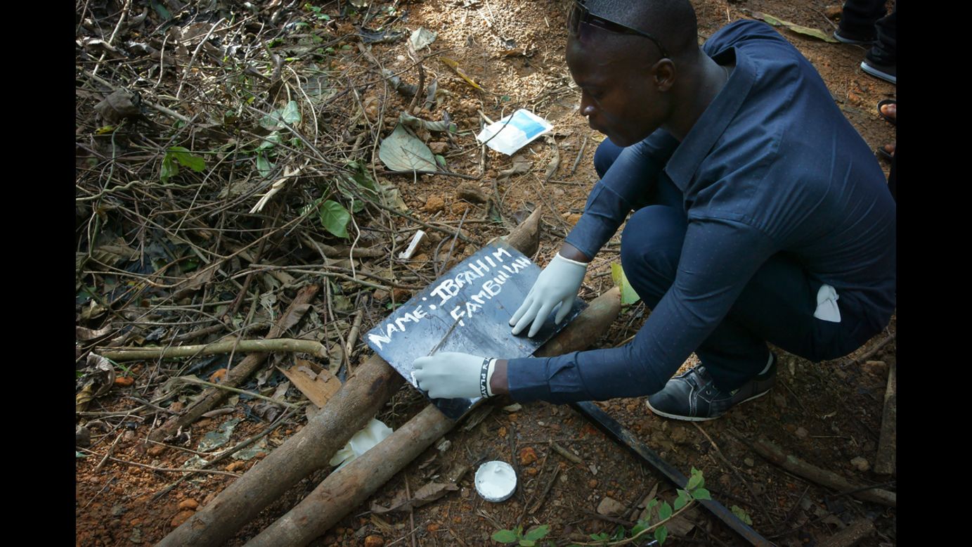 A man writes the name of another man, Ibrahim Fambullah, who died of ebola, on an iron slab in the area of the cemetery reserved for the deaths of Ebola. (Luigi Baldelli/ECHO)