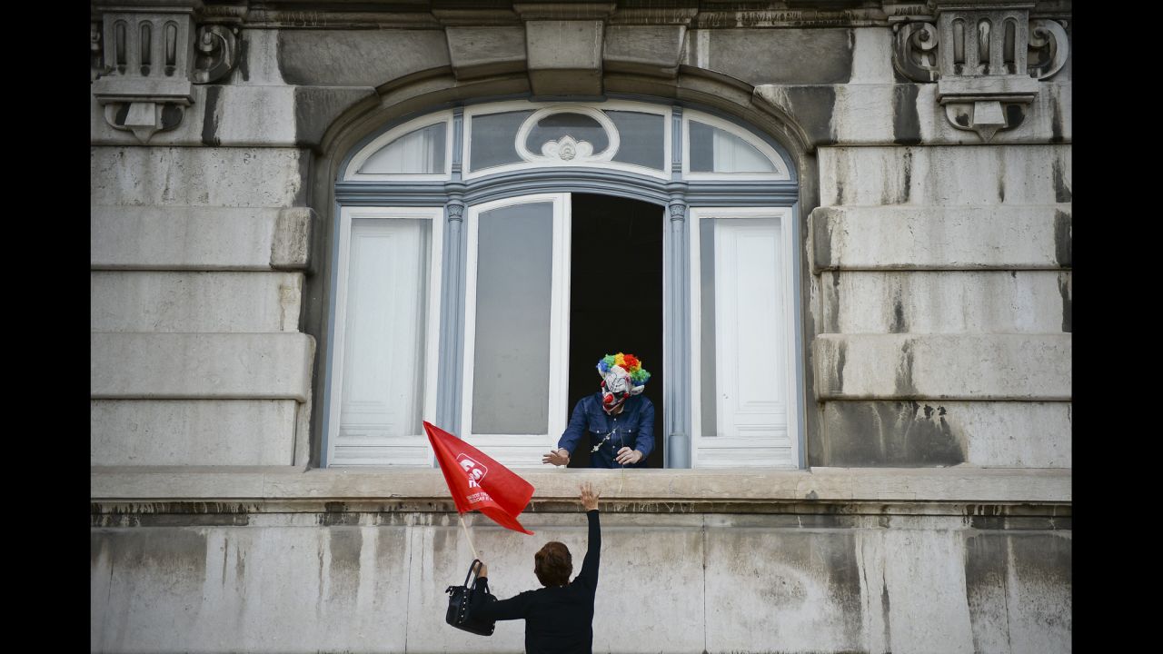 A demonstrator waves to a man dressed up as a clown during a demonstration against wage cuts and increased working hours in Lisbon, Portugal, on Friday, October 31.