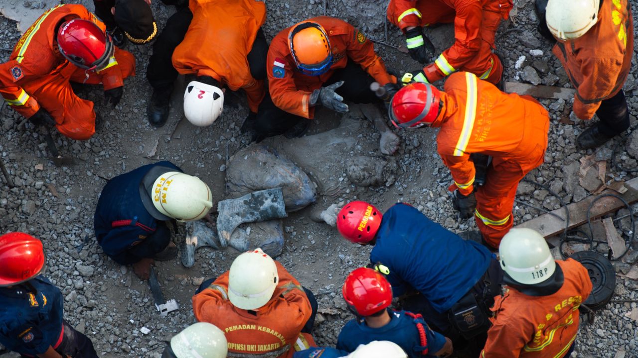 Rescuers gather around a body during search operations after a building collapsed in Jakarta, Indonesia, on Friday, October 31.