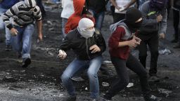 Masked Palestinian youths throw stones during clashes with Israeli security forces in the Palestinian refugee camp of Shuafat in east Jerusalem, on November 7, 2014