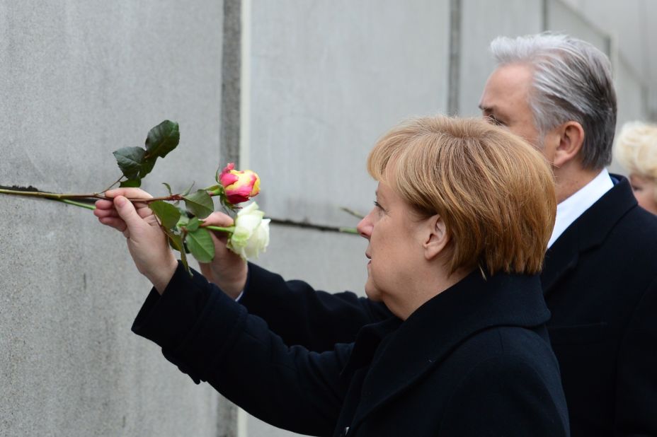 German Chancellor Angela Merkel and Berlin Mayor Klaus Wowereit place roses in the preserved segment of the wall.