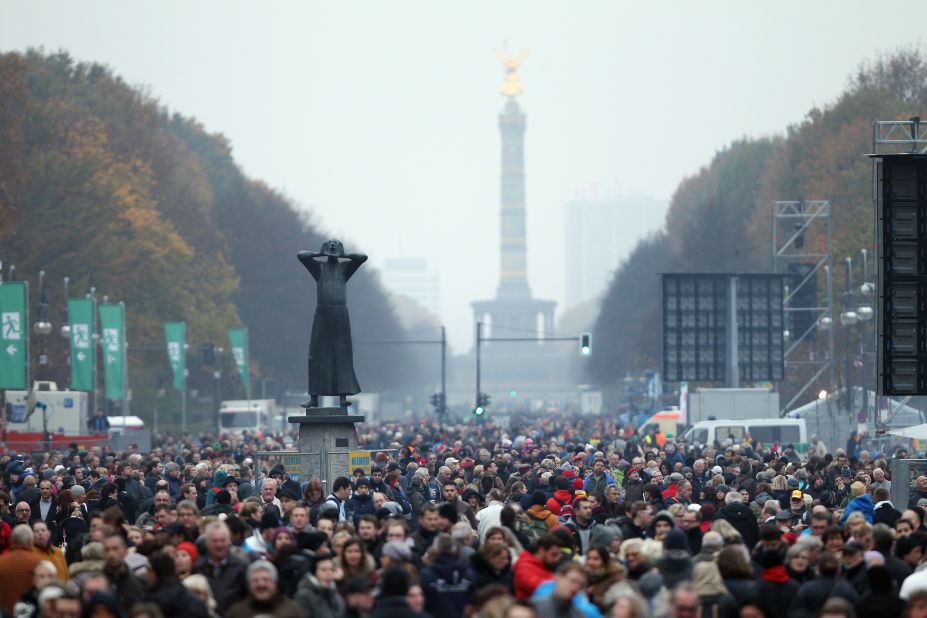 A statue called "Der Rufer" ("The Caller"), who is yelling to the east demanding freedom, stands over crowds gathered to celebrate the anniversary. 
