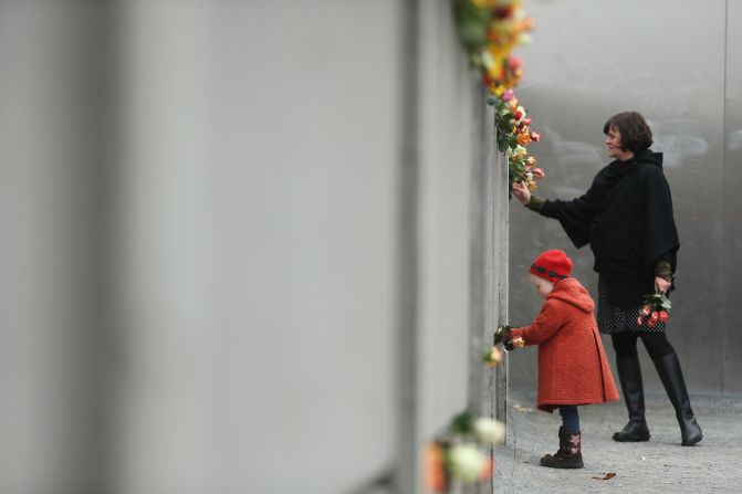 Hulda, de 3 años, pone flores entre las grietas del antiguo Muro de Berlín en Bernauer Strasse el 9 de noviembre de 2014.