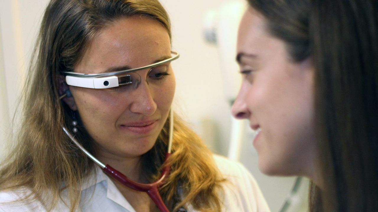 A doctor wearing Google Glass treats a patient. Google is working with companies on bringing the wearable into workplaces to improve productivity. 