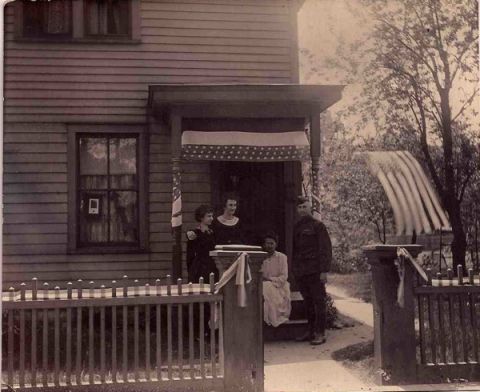 Back home in 1919, Foster joins his mother and two sisters outside their La Crosse, Wisconsin, house, which was draped in red, white and blue decorations. 