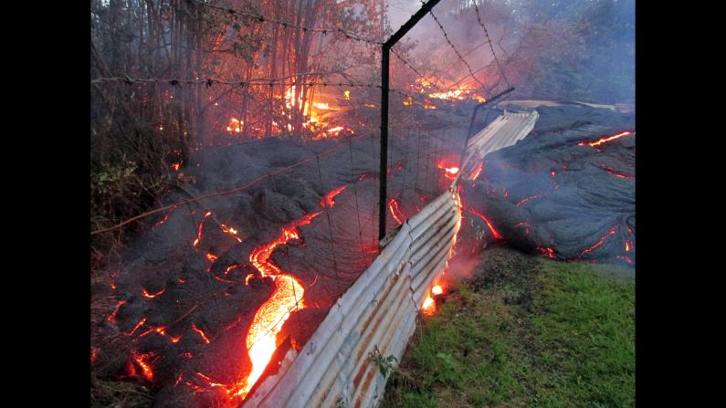 Lava flows over a fence marking a property line near the town of Pahoa on Friday, October 31. 