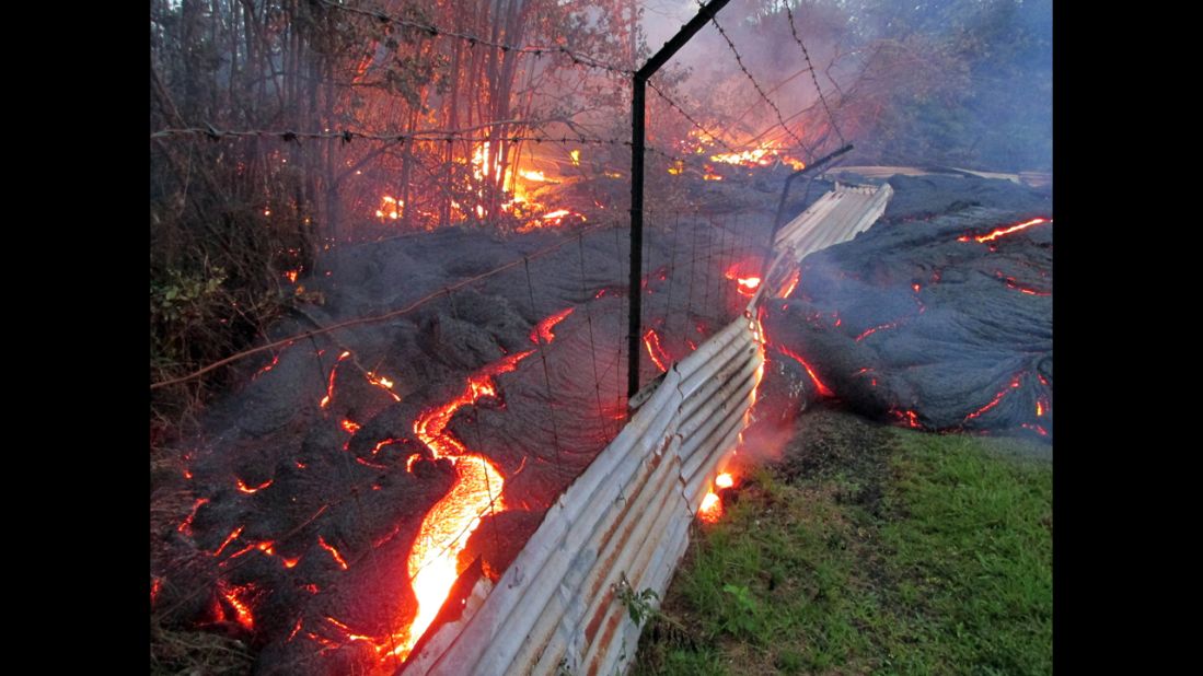 Lava flows over a fence marking a property line near the town of Pahoa on Friday, October 31. 