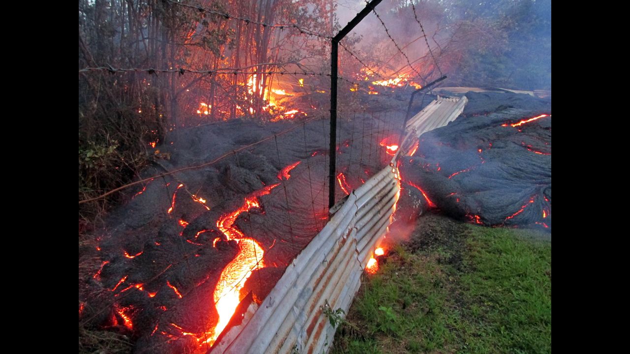 Lava flows over a fence marking a property line near the town of Pahoa on Friday, October 31.