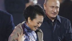 In this Nov. 10, 2014 file photo, Russia's President Vladimir Putin, right, puts a shawl on Peng Liyuan, second right, wife of Chinese President Xi Jinping, seated second left talking to U.S. President Barack Obama, left, as they arrive to watch a fireworks show after a welcome banquet for the Asia Pacific Economic Cooperation (APEC) summit in Beijing. It was a warm gesture on a chilly night when Vladimir Putin wrapped a shawl around the wife of Xi Jinping while the Chinese president chatted with Barack Obama. The only problem: Putin came off looking gallant, the Chinese summit host gauche and inattentive. (AP Photo, File) CHINA OUT