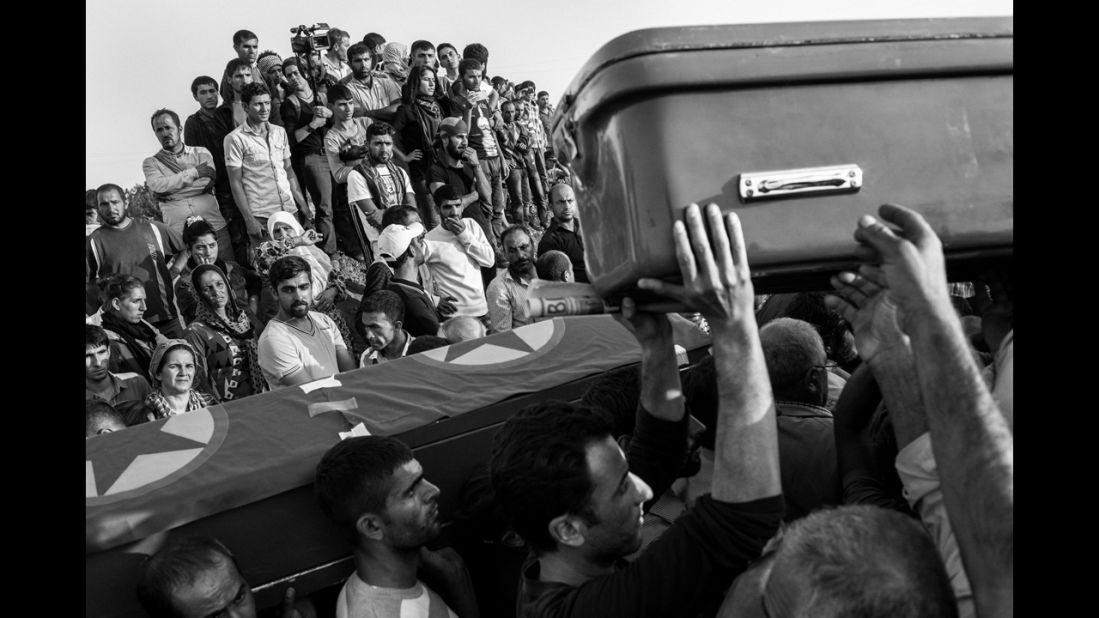 Refugees watch the procession of soldiers being buried in Turkey.