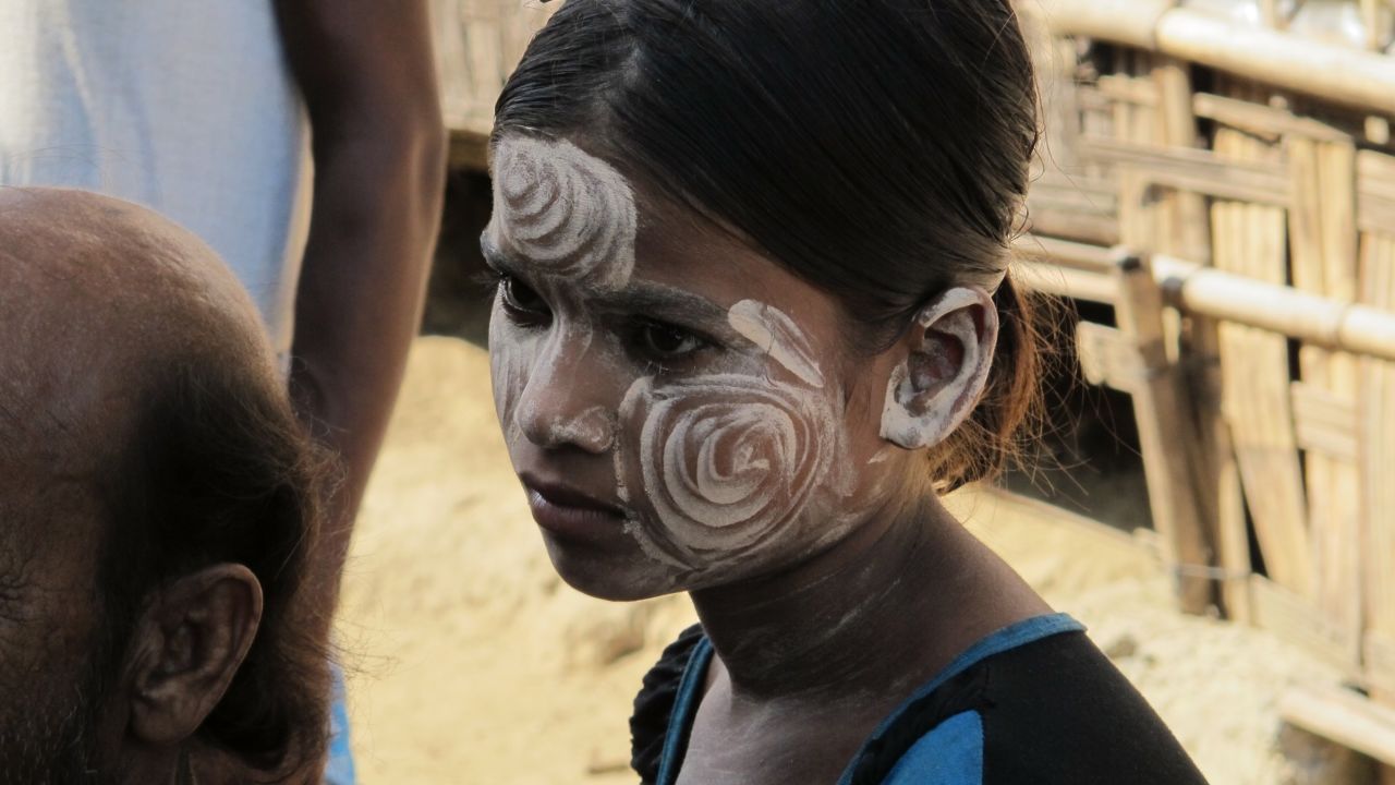 A young Muslim girl wears the traditional thanakha on her face. Thanakha is a paste made from ground bark that protects the skin from the sun and is appreciated for its aesthetic appeal.