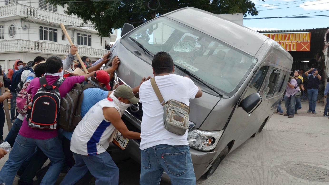 Manifestantes vuelcan un vehículo durante un enfrentamiento con la policía antimotines en Chilpacingo, el martes 11 de noviembre.