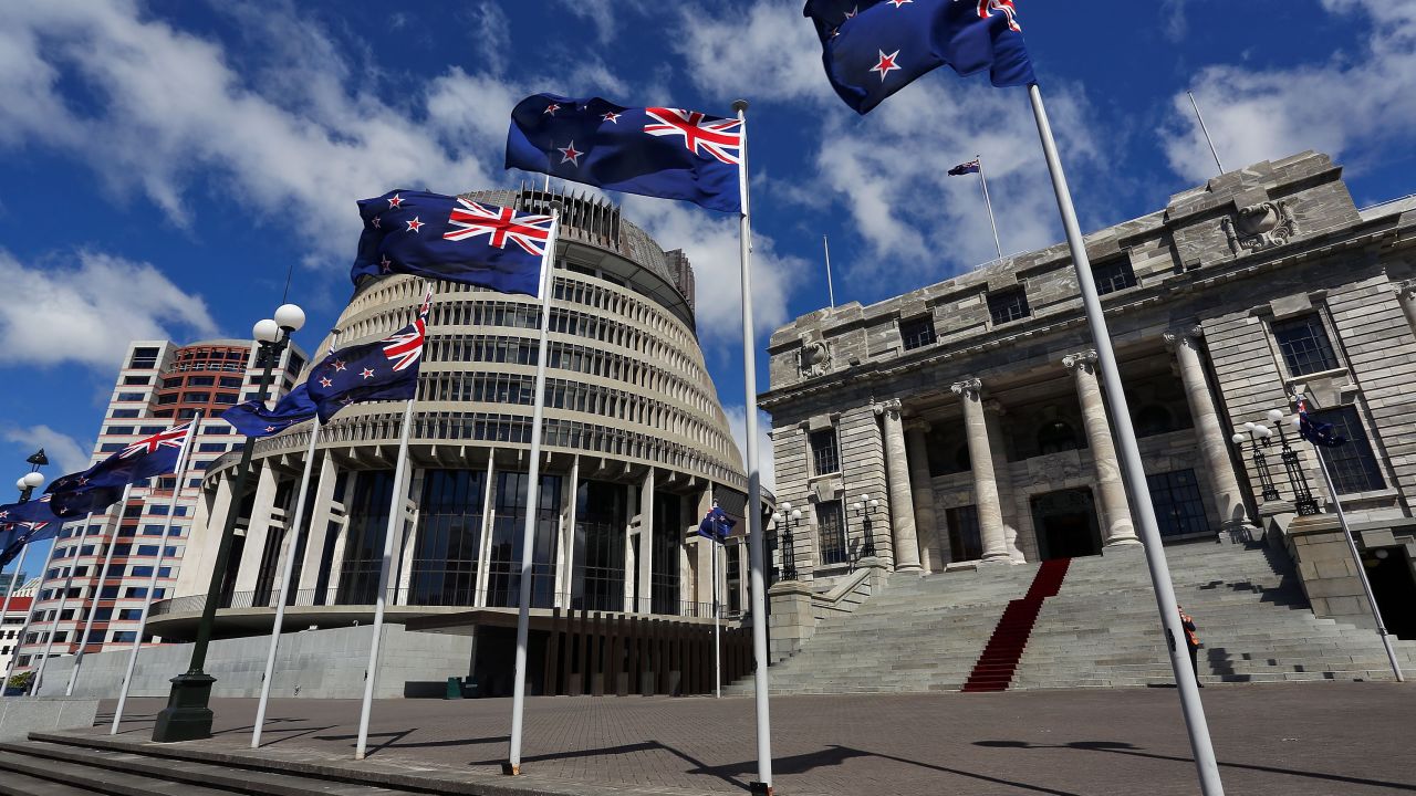 New Zealand flags fly in front of The Beehive and Parliament House in Wellington, New Zealand.