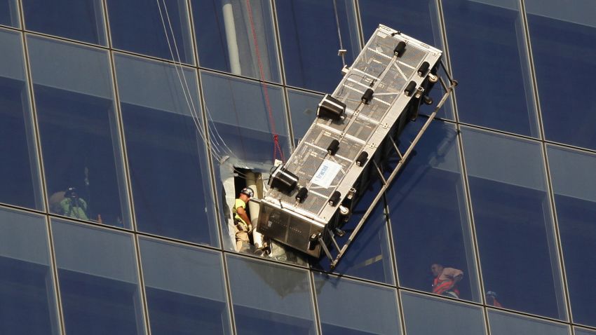 Workers look out at a broken scaffolding that had stranded window washers earlier on the side of 1 World Trade Center in New York November 12, 2014. Two window washers caught on dangling scaffolding on the 69th floor of New York City's 1 World Trade Center were pulled to safety on Wednesday through a window cut in the tallest U.S. skyscraper, a building official said.