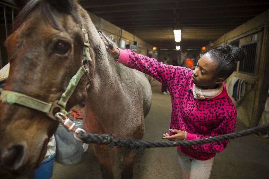 A young program participant grooms her horse inside a stable at the equestrian center. "We use horses as a hook to create pride, esteem and healing," Kelly said. "They learn that they have ability. They just have to unlock it."