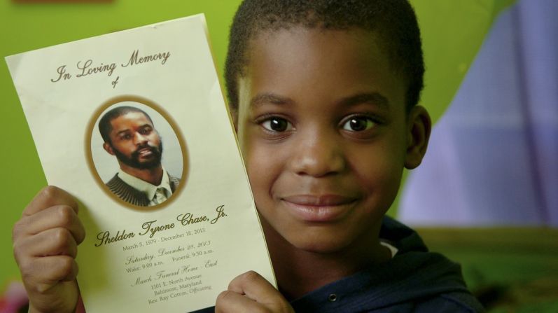 Kyron Chase, 7, holds up a leaflet from his father's funeral. Kyron and his mom have been attending sessions at Roberta's House, and his mom says he is opening up more about his feelings and his dad.