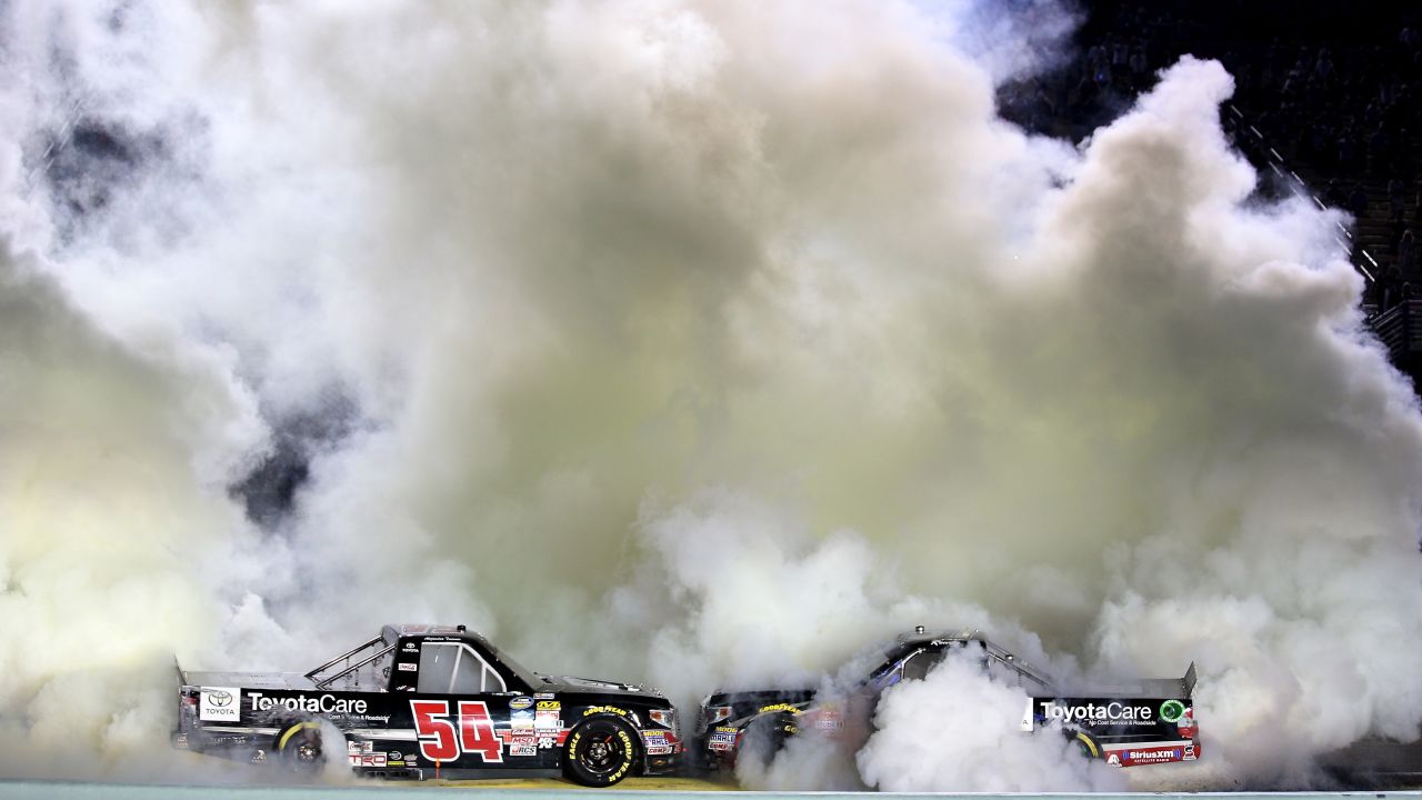 The trucks of Darrell Wallace Jr., left, and Matt Crafton burn rubber at Homestead-Miami Speedway on Friday, November 14. Wallace was celebrating his win in that night's NASCAR Truck Series race. Crafton was celebrating because he won the series championship.