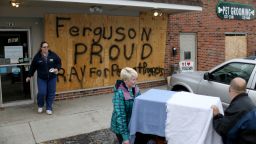 FERGUSON, MO - NOVEMBER 17: Melisa Hutchings (L), Tracy Reust and Daniel Wentz walk past a sign reading, "Ferguson Proud Pray for Peace and Progress, " as they carry a cat from the Ferguson Animal Hospital where they placed plywood on the windows to try to protect the business from any violent reaction to the grand jury decision on November 17, 2014 in Ferguson, Missouri. The area around St Louis, Missouri prepares for the release of the grand jury decision in the shooting death of Michael Brown by Darren Wilson, a Ferguson police officer. (Photo by Joe Raedle/Getty Images)