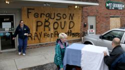 	FERGUSON, MO - NOVEMBER 17: Melisa Hutchings (L), Tracy Reust and Daniel Wentz walk past a sign reading, "Ferguson Proud Pray for Peace and Progress, " as they carry a cat from the Ferguson Animal Hospital where they placed plywood on the windows to try to protect the business from any violent reaction to the grand jury decision on November 17, 2014 in Ferguson, Missouri. The area around St Louis, Missouri prepares for the release of the grand jury decision in the shooting death of Michael Brown by Darren Wilson, a Ferguson police officer. (Photo by Joe Raedle/Getty Images)