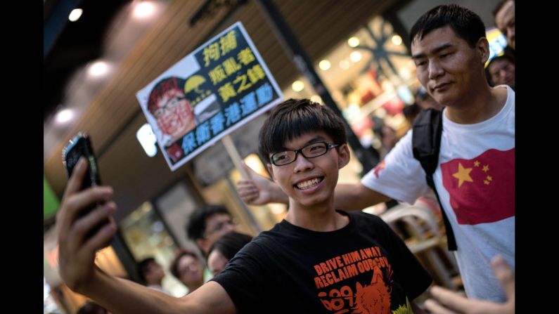 Student activist Joshua Wong snaps a photo next to a pro-Beijing activist who had been shouting slogans at him while he handed out flyers in Hong Kong on Sunday, November 16. Wong founded the pro-democracy student group Scholarism. <a href="http://www.cnn.com/2014/09/21/world/asia/hong-kong-joshua-wong-democracy-protest/">His goal</a> is to pressure China into giving Hong Kong full universal suffrage.