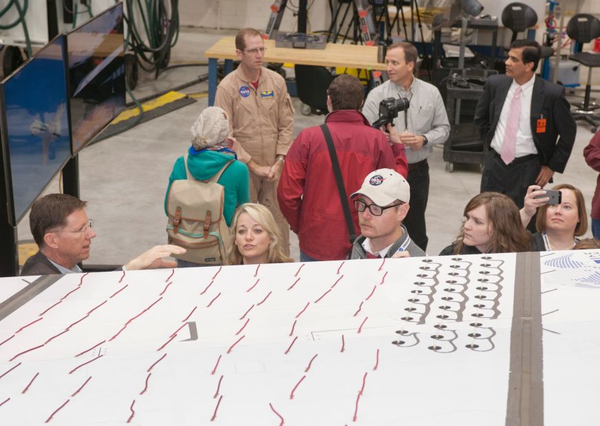 NASA's ongoing project -- the Adaptive Compliant Trailing Edge project, or ACTE -- could save hundreds of millions of dollars a year in fuel costs. NASA test pilot Tim Williams (rear left) discusses an adaptive wing flap on a Gulfstream III. 
