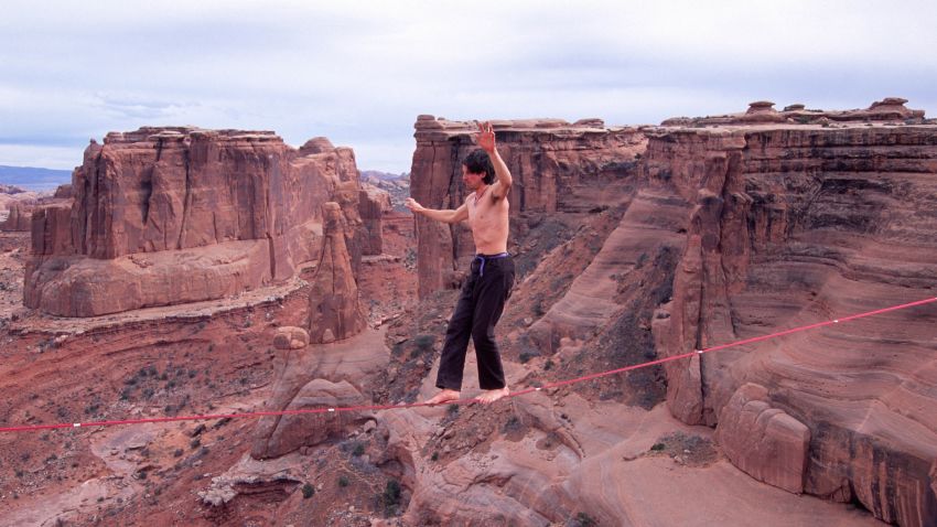 Dean Potter highlines at the Three Gossips in Utah's Arches National Park. Unlike tightrope walking, highlighers must maintain their balance on a slack line instead of a taut one. Potter has completed a number of highline crossings without safety equipment.