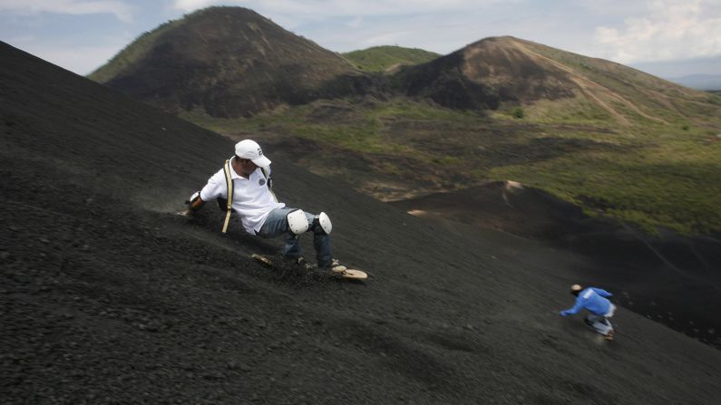 Dos hombres se deslizan por el volcán Cerro Negro en la ciudad de León, Nicaragua. El Cerro Negro es uno de los volcanes más activos de Nicaragua y es un lugar popular para el deporte del descenso en tablas por el volcán.