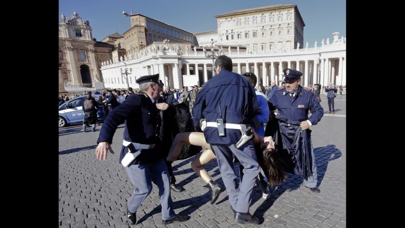 Police officers at the Vatican carry away an activist during a protest Friday, November 14, in St. Peter's Square. The Ukrainian feminist group Femen was protesting the Pope's upcoming visit to the European Parliament and Council.