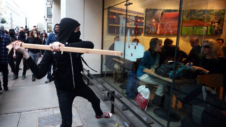 A protester in London tries to smash a Starbucks window Wednesday, November 19, during a demonstration against fees and cuts in the education system. 