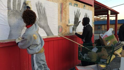 Martez Davis, left, and Anthony Gatling, 19, help put up Damon's art on boarded up Red's Barbecue restaurant.

