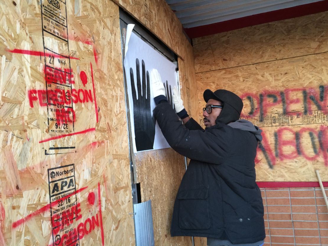 St. Louis artist Damon Davis puts up one of his posters. He wants them to serve as a message of hope for Ferguson.


