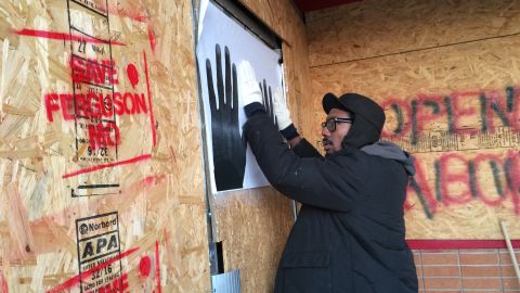 St. Louis artist Damon Davis puts up one of his posters. He wants them to serve as a message of hope for Ferguson.