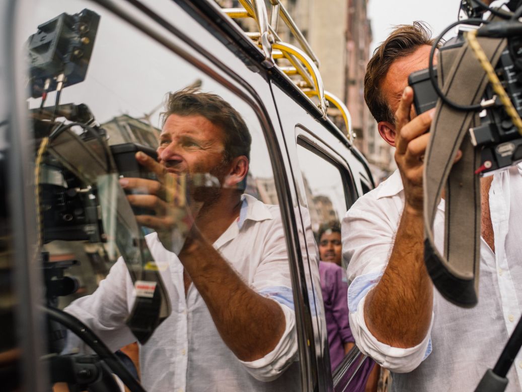 Philip Bloom is reflected in a car window while shooting around Mumbai.  