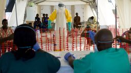 Caption:A health worker wearing a protective suit assists patients at the Ebola treatment centre run by French Red Cross in Macenta on November 21, 2014. The World Health Organisation said that 5,420 people have so far died of Ebola across eight countries, out of a total 15,145 cases of infection, since late December 2013. AFP PHOTO/KENZO TRIBOUILLARD (Photo credit should read KENZO TRIBOUILLARD/AFP/Getty Images)