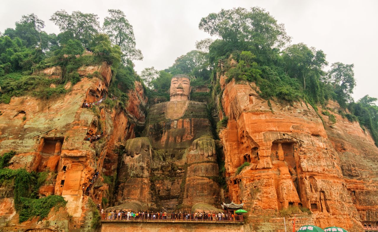 This file photo shows tourists at the feet of the giant Buddha, which is usually untroubled by river water.