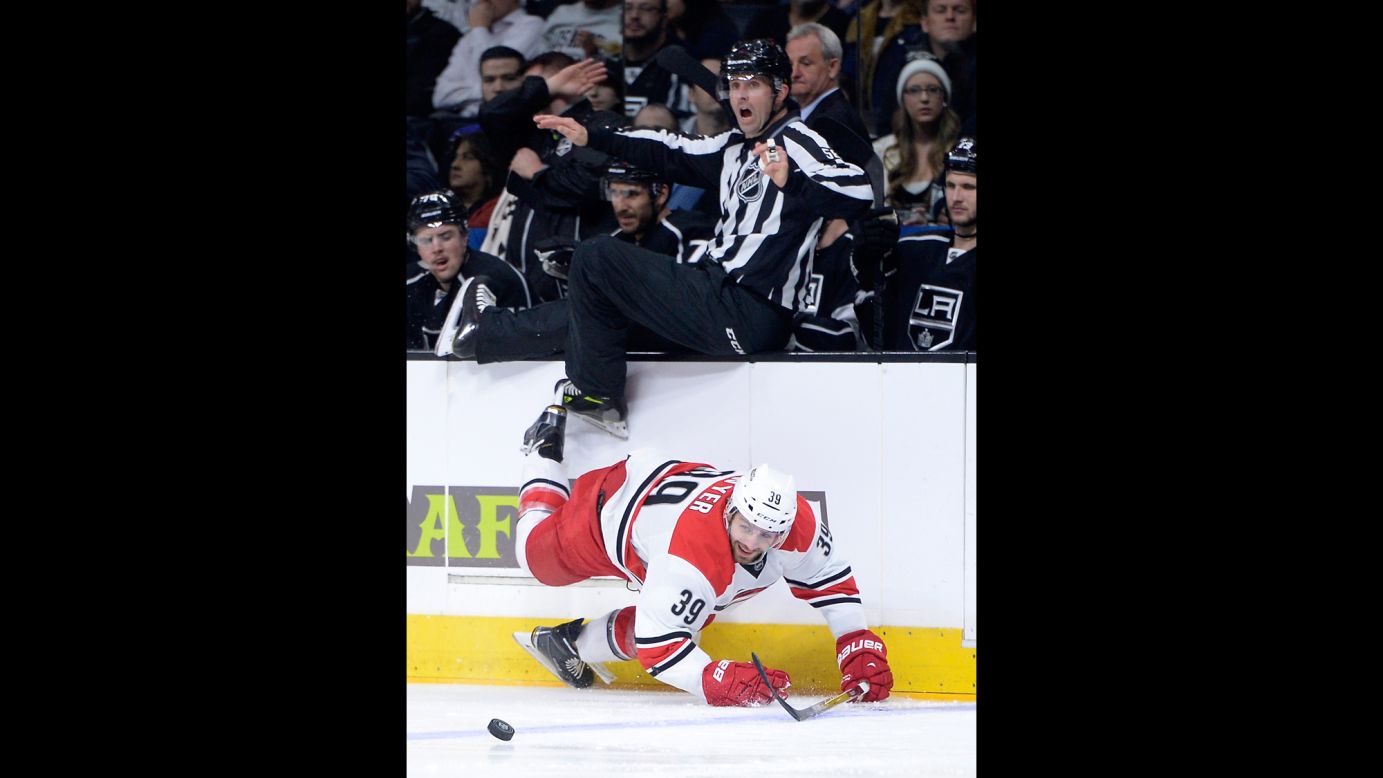 An NHL linesman jumps out of the way as Carolina's Patrick Dwyer falls while chasing the puck Thursday, November 20, in Los Angeles.